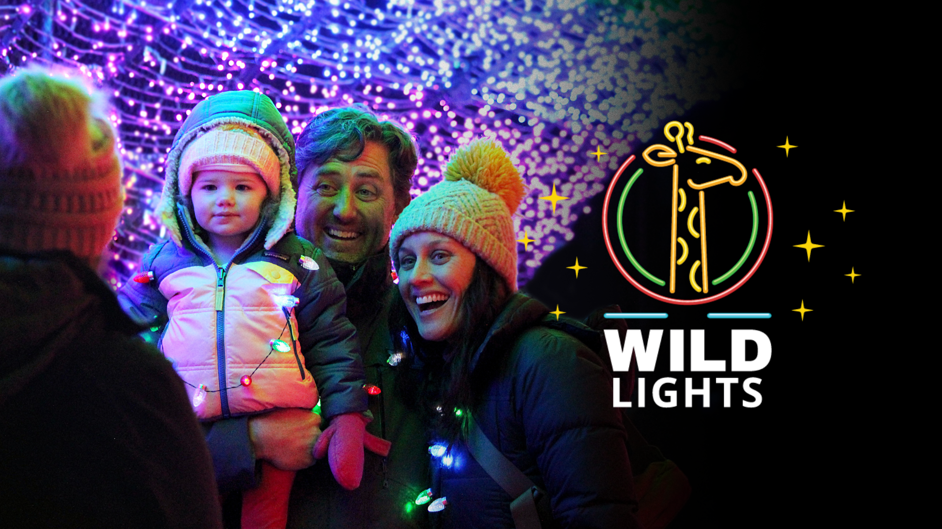 a photo of a family, smiling, enjoying the zoo's annual light christmas display.